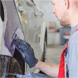 Person working on a car in a garage applying filler with a plastic spreader